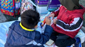Two migrant children eating peanut butter and jelly sandwiches passed out by volunteers, and who cannot find shelter. 100 sandwiches were distributed in less than 15 minutes. 